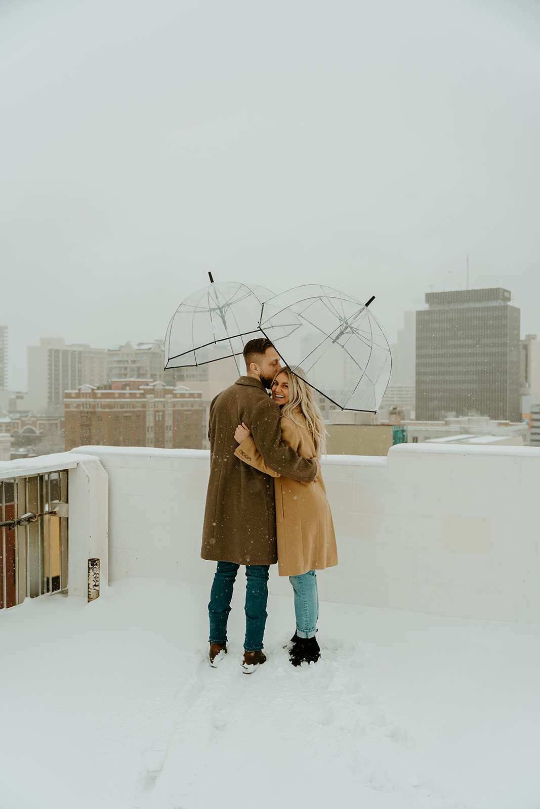 A couple snuggled up in the snow on the rooftop of a downtown reno parking garage. 