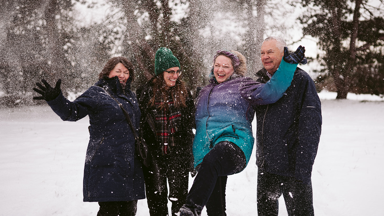 Family laughing and kicking up snow together