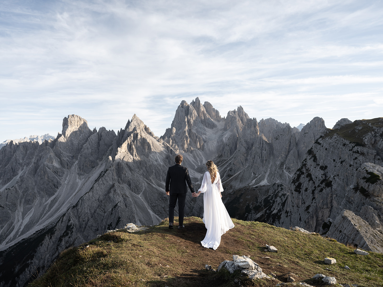 couple on their wedding day holding hands and looking at the view of the mountains in the dolomites 