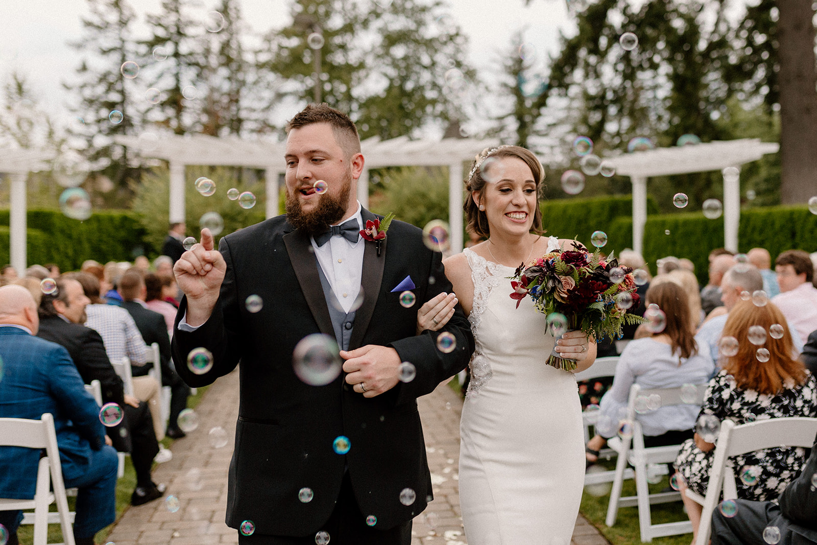A groom pops a bubble as he walks down the aisle after his wedding ceremony at The Aerie at Eagle Landing. 
