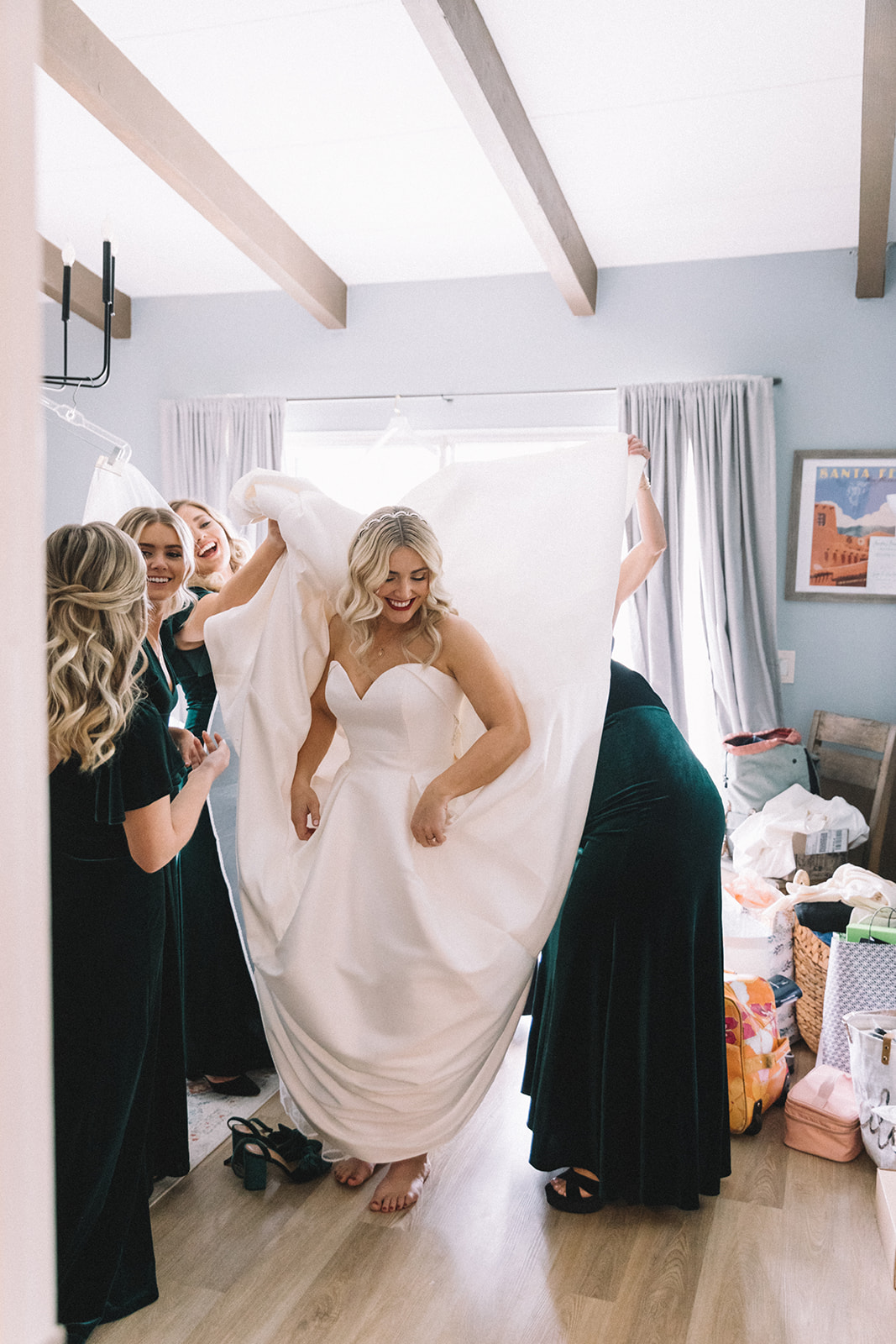 Bride gets dressed in her bridal gown surrounded by her best friends in their emerald bridesmaids dresses.