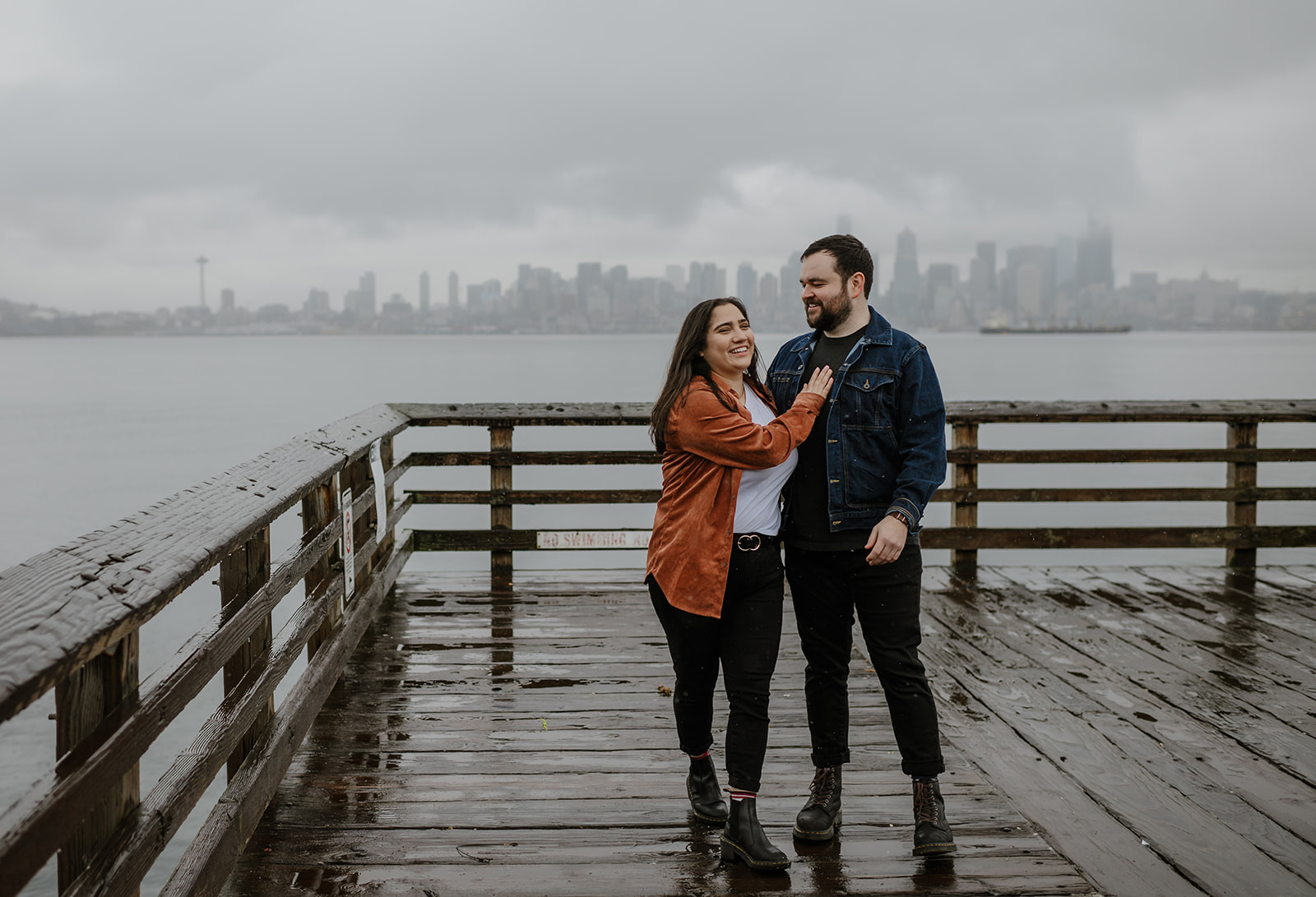 a couple walks together down the pier on a rainy day laughing together