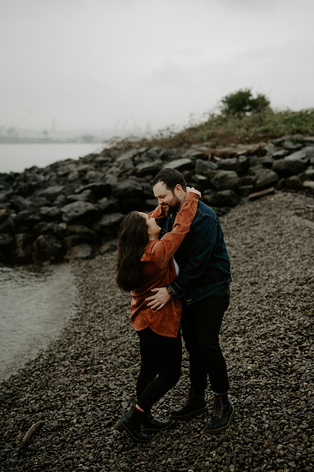 a couple embraces at the beach on a rainy day