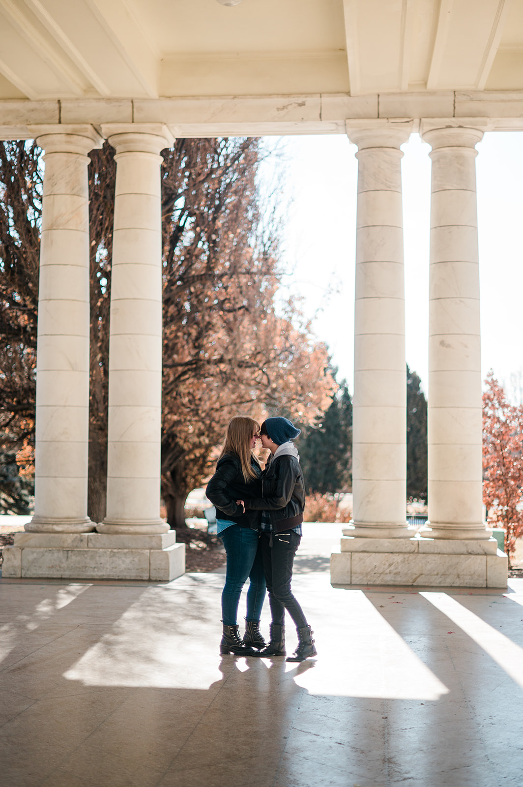 photo of two women snuggling in pretty light between marble pillars in a pavilion 