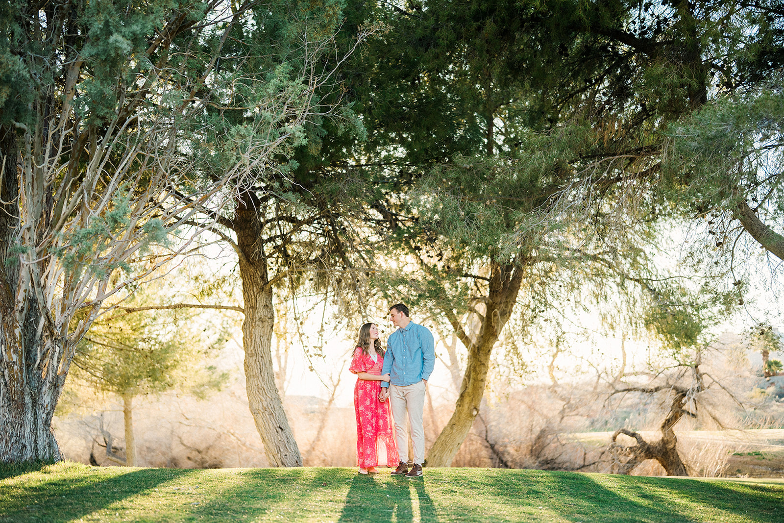 couple looks at each other in front of trees at golf corse