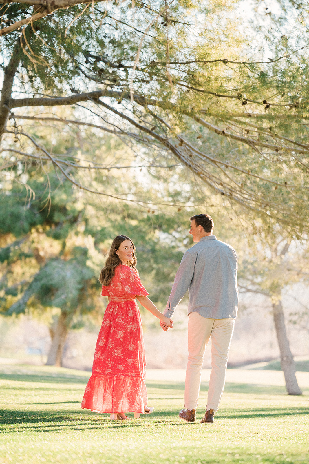 engaged couple walks away from camera playfully