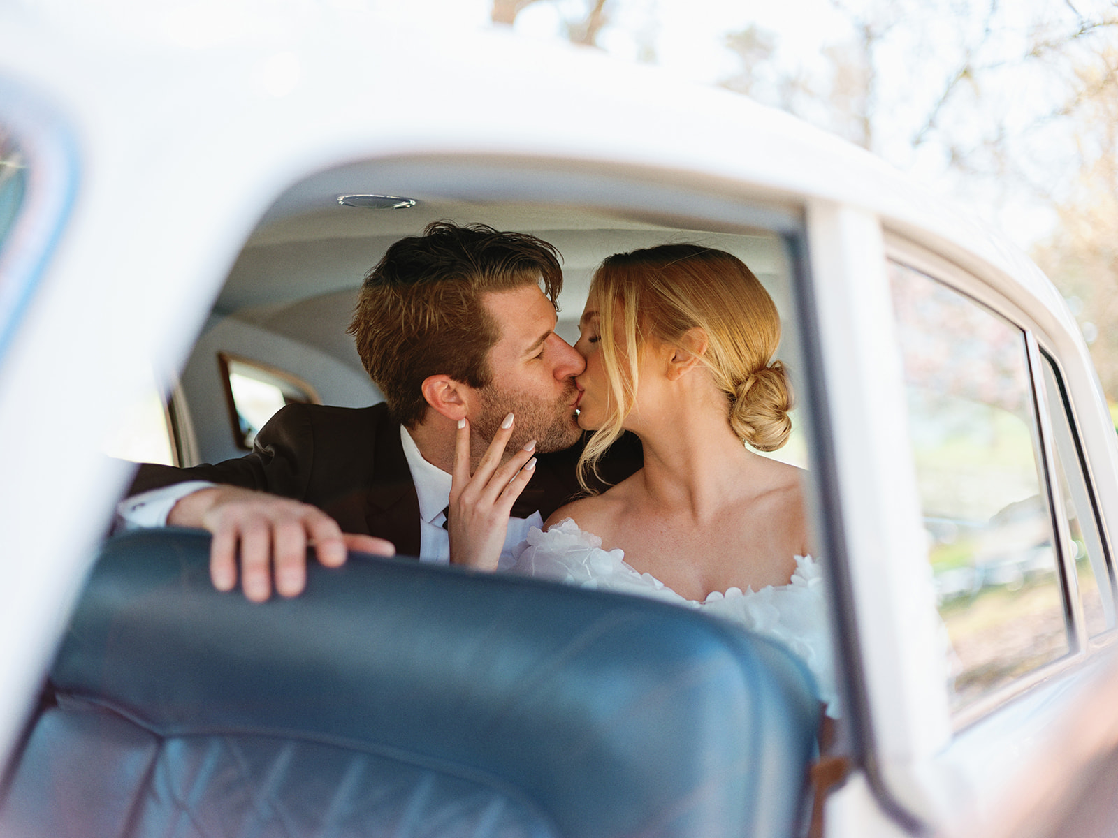 Bride and groom kissing in classic rolls-royce car
