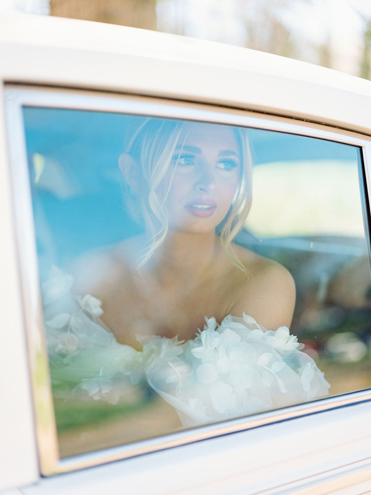 Bride staring out window in classic rolls-royce car
