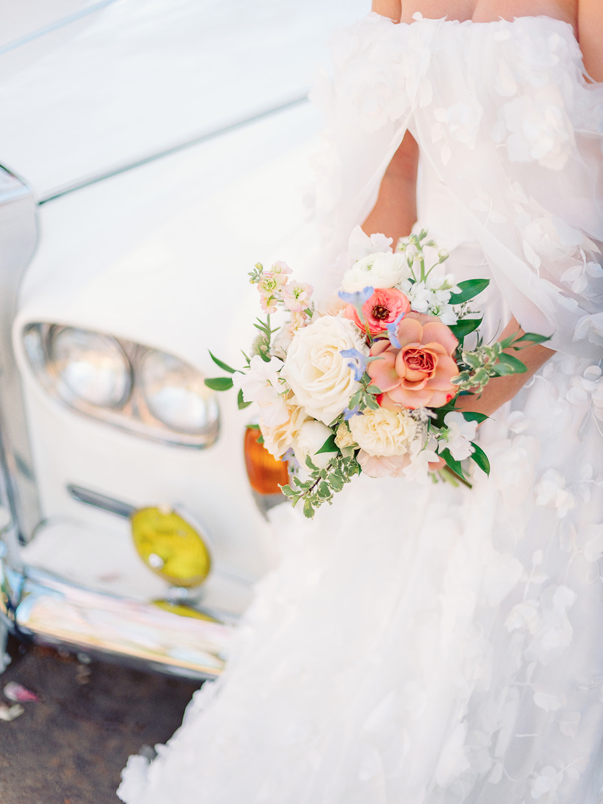 Bride's bouqet with a classic rolls-royce car
