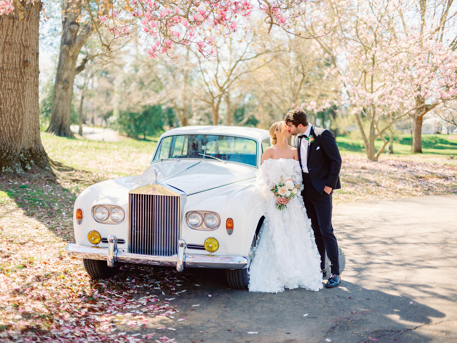 Trendy couple kissing in front of classic Rolls-royce car