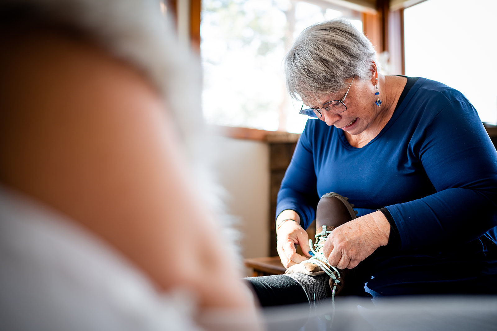 Mom helps to lace up her daughter's hiking boots that she is wearing on her elopement day in Colorado