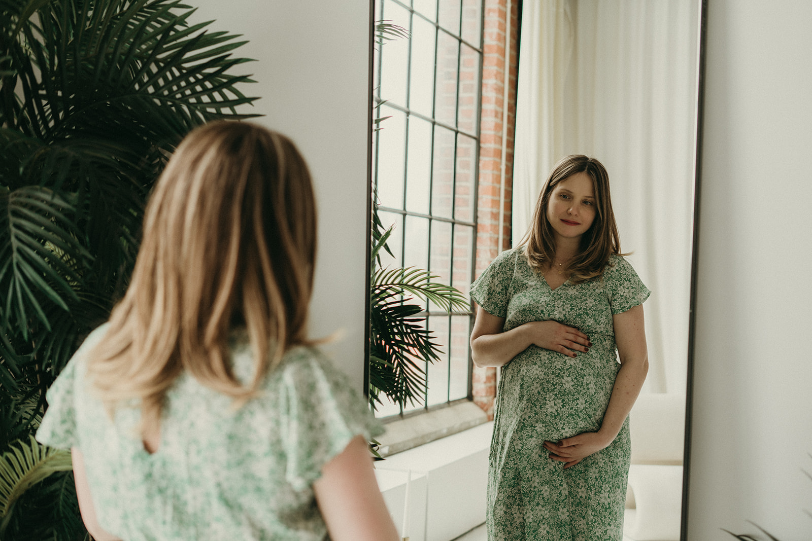 Maternity photo of mother holding belly in mirror