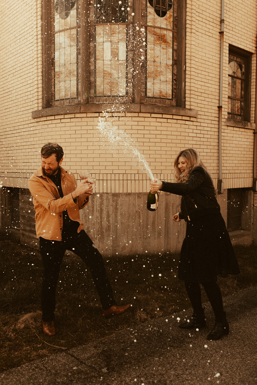 couple laughing and popping champagne to celebrate cincinnati engagement photos