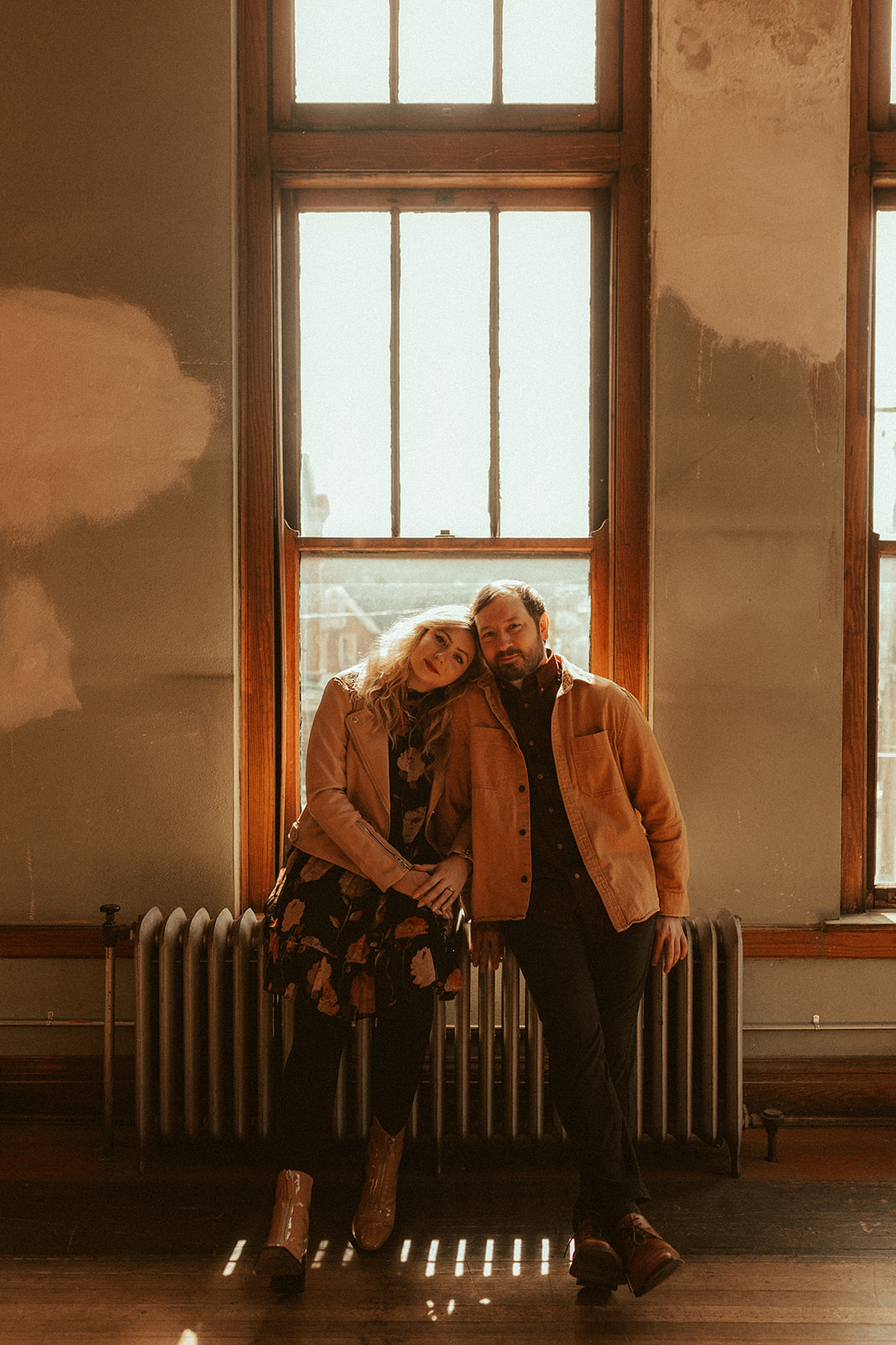 couple sitting on radiator in front of victorian windows