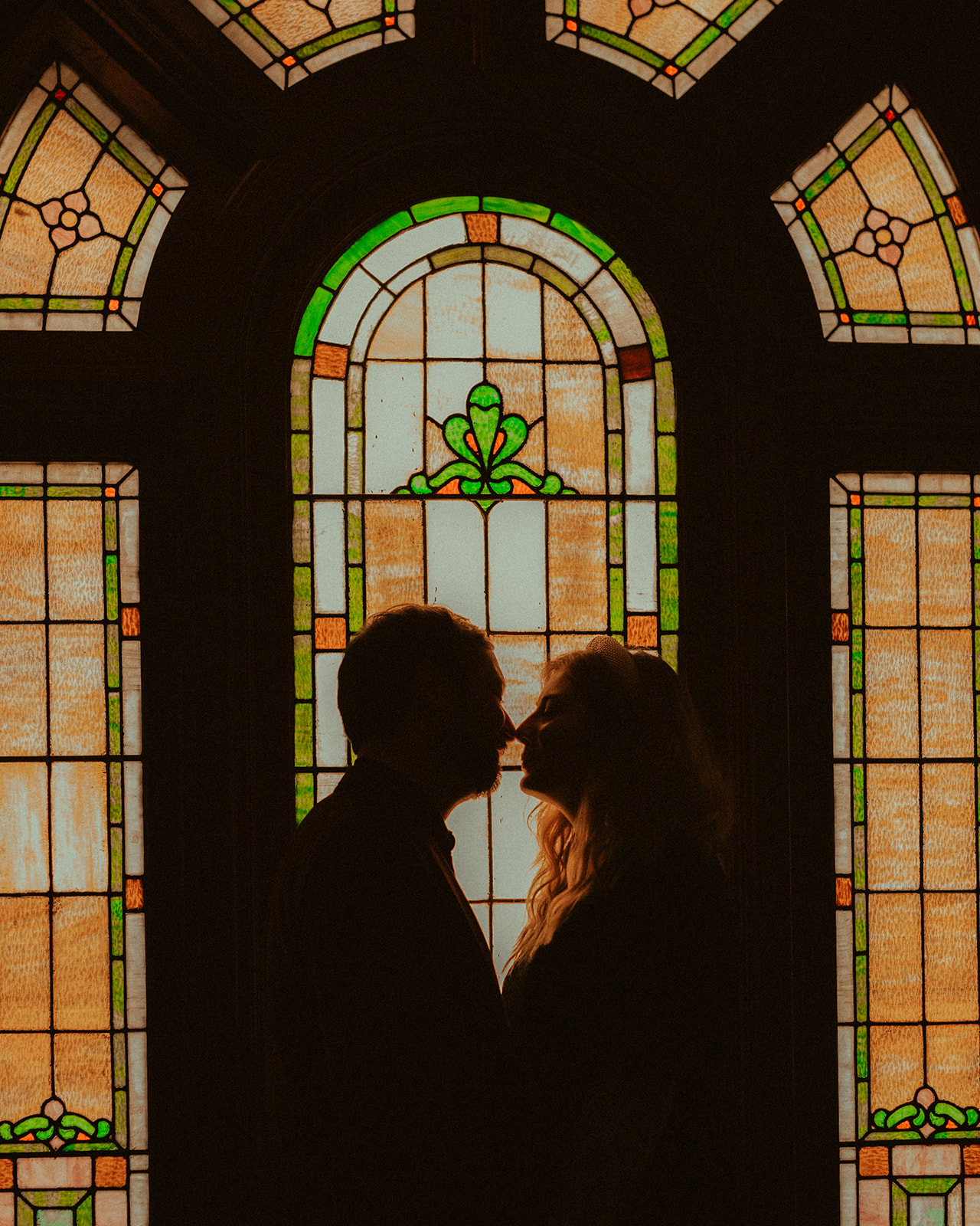 romantic cinematic engagement photo in front of 1890's vintage stained glass window