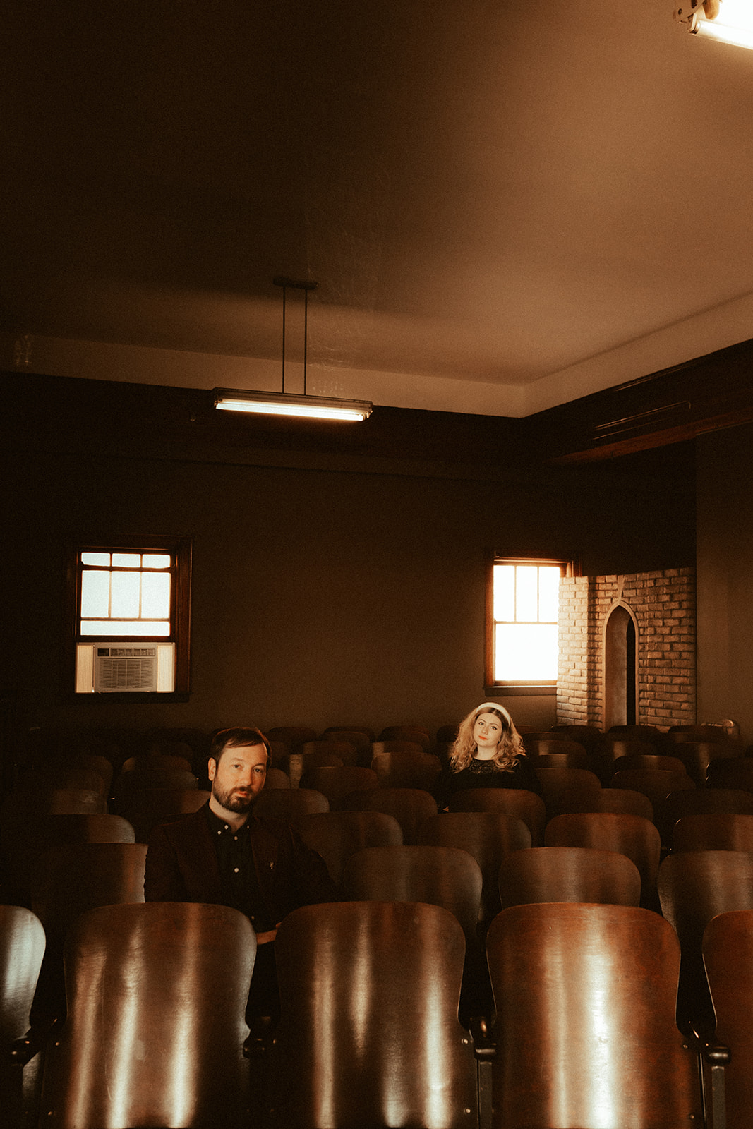 couple sitting in auditorium seats for vintage engagement photos
