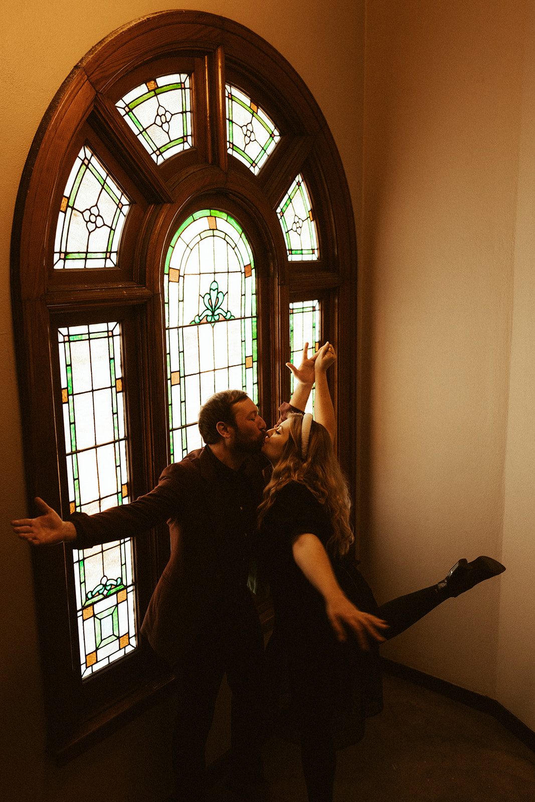 couple kissing in front of vintage stained glass window