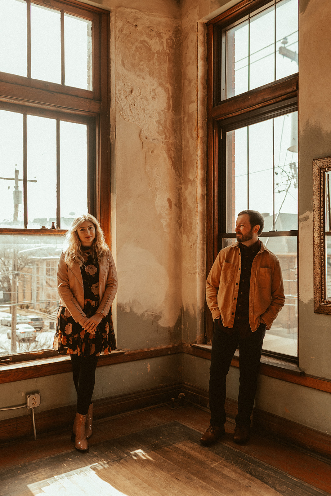 couple standing side by side in front of vintage windows