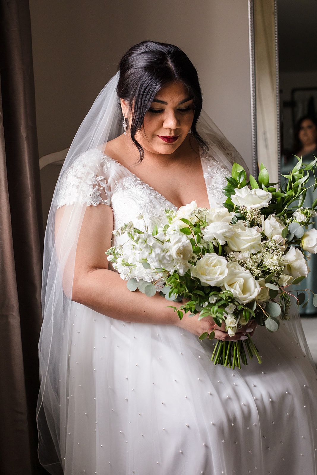 Bride admires her all-white bouquet