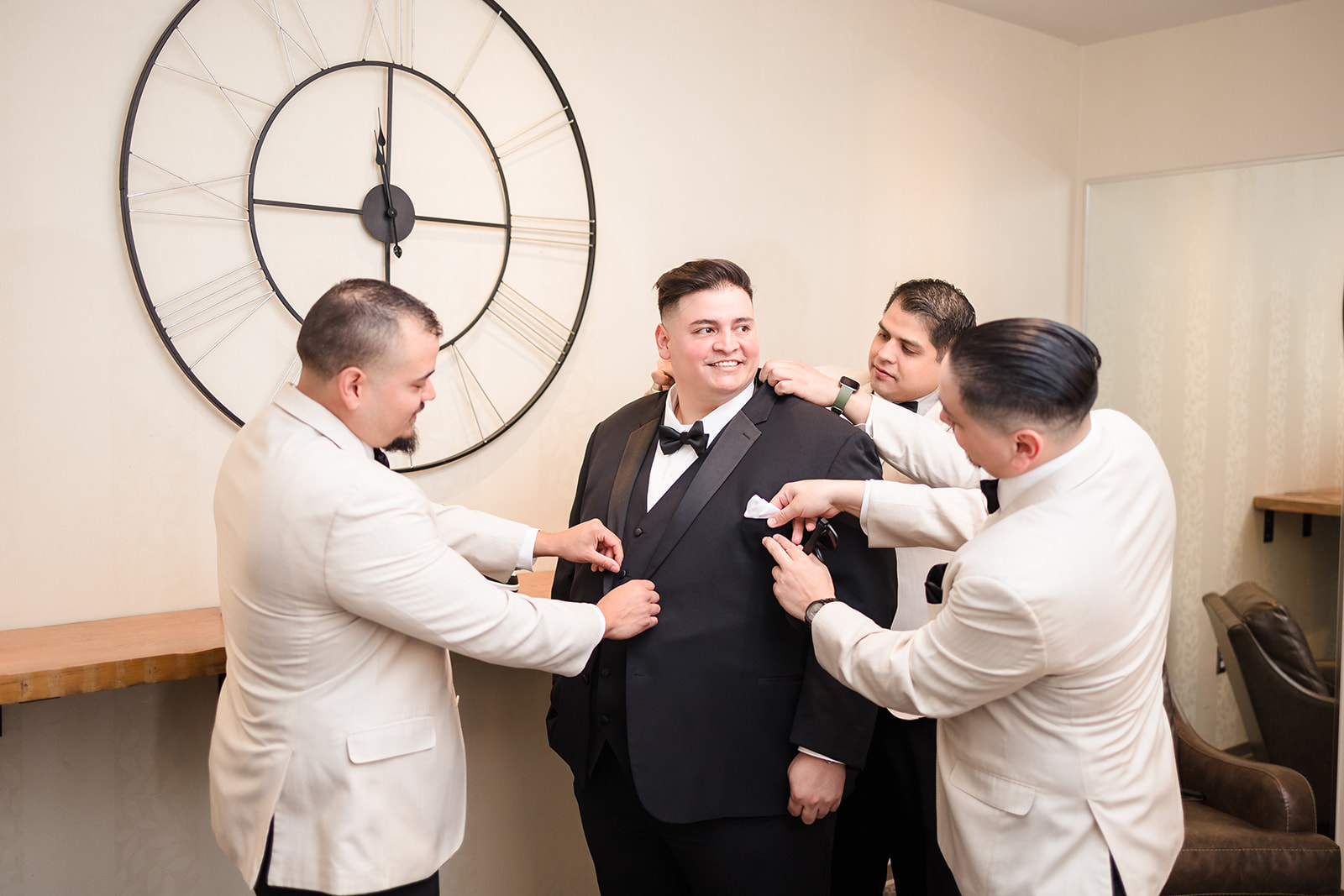Groomsmen help the groom put on the finishing touches before his wedding