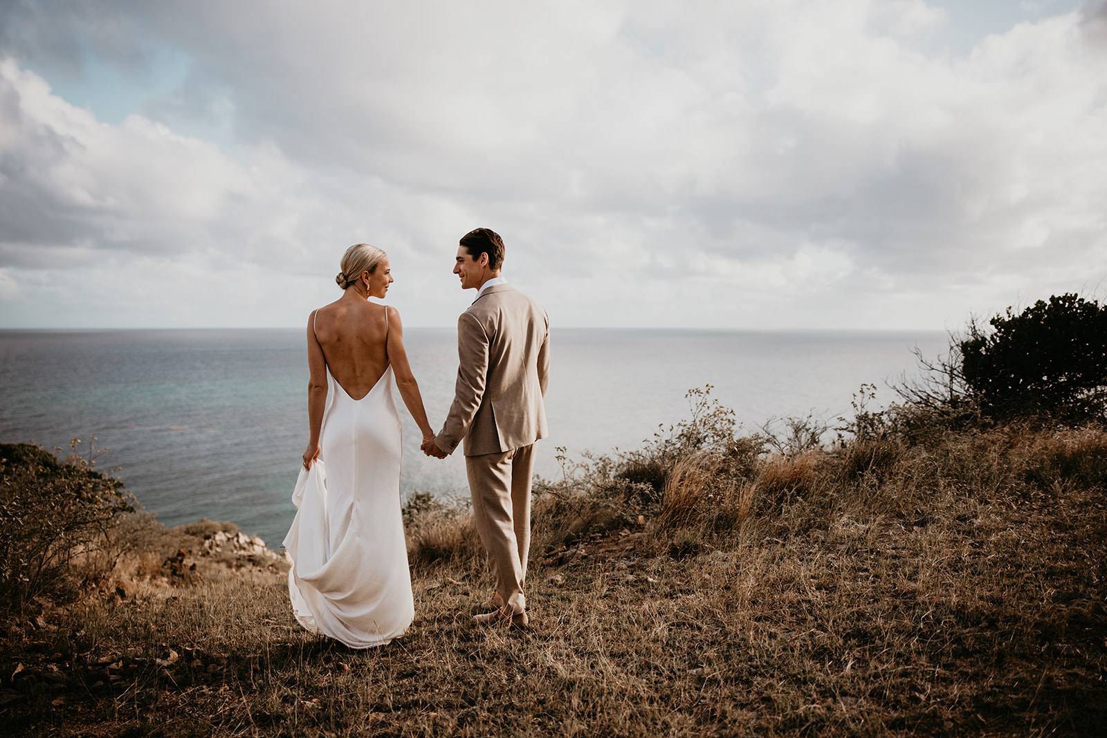 Candid moment of the bride and groom walking along a rocky shoreline in the British Virgin Islands