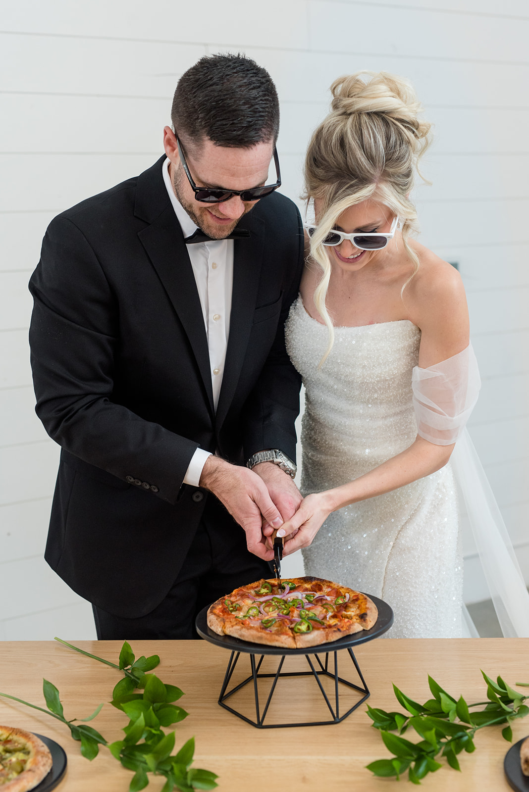 Bride and groom cut a pizza together at their wedding reception