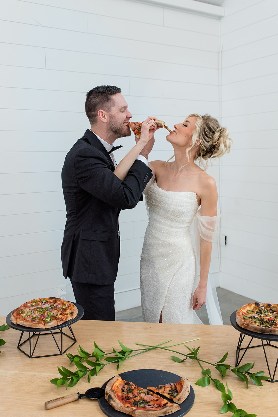 Bride and groom feed each other pizza at their wedding reception