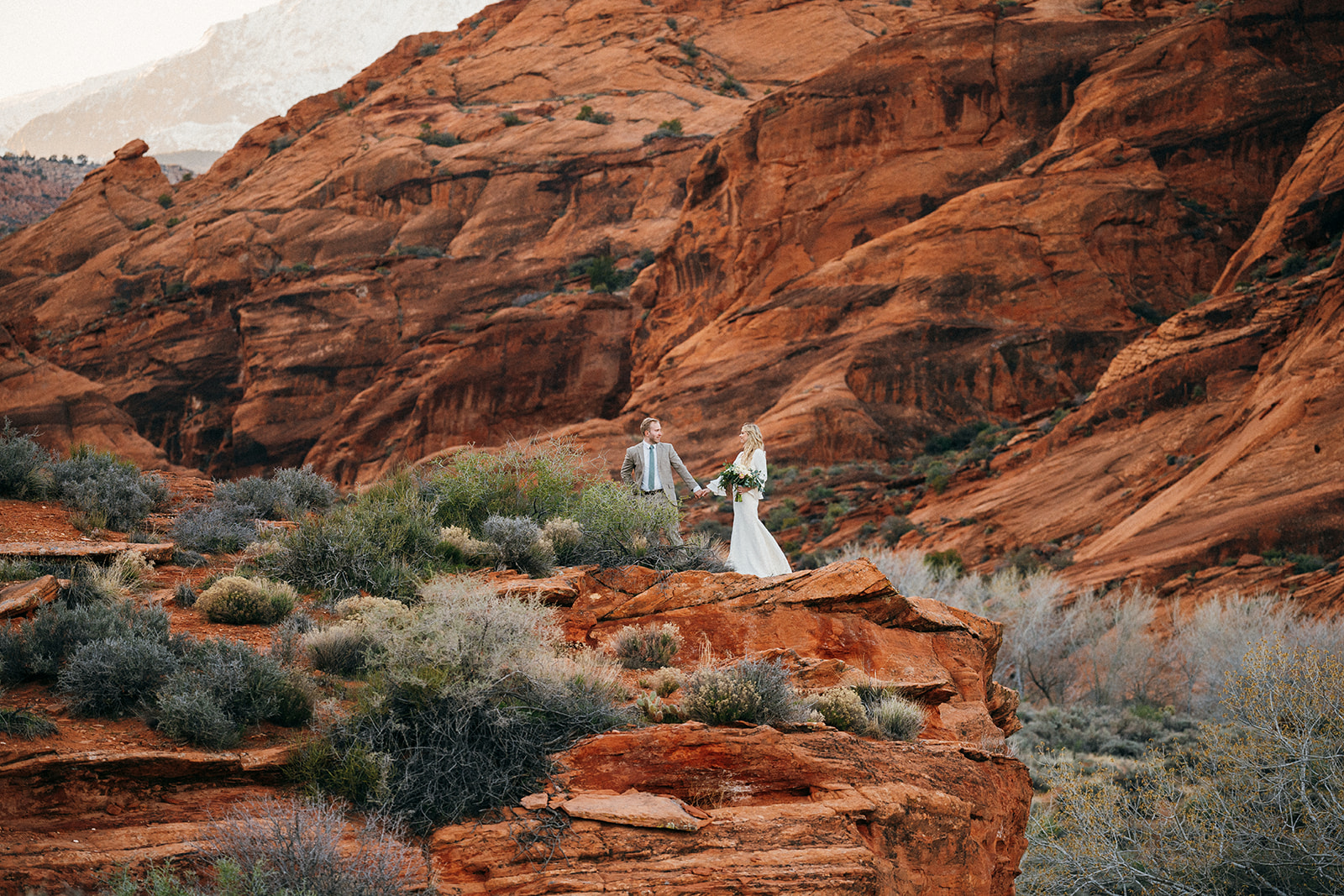 couple walking away from red rock cliff