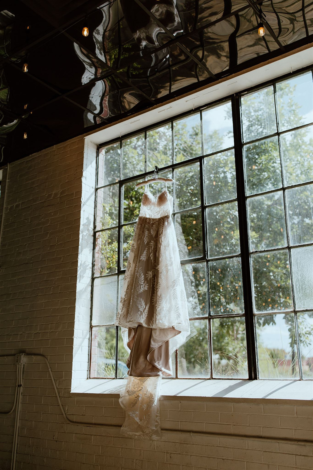Wedding dress hangs from an industrial window
