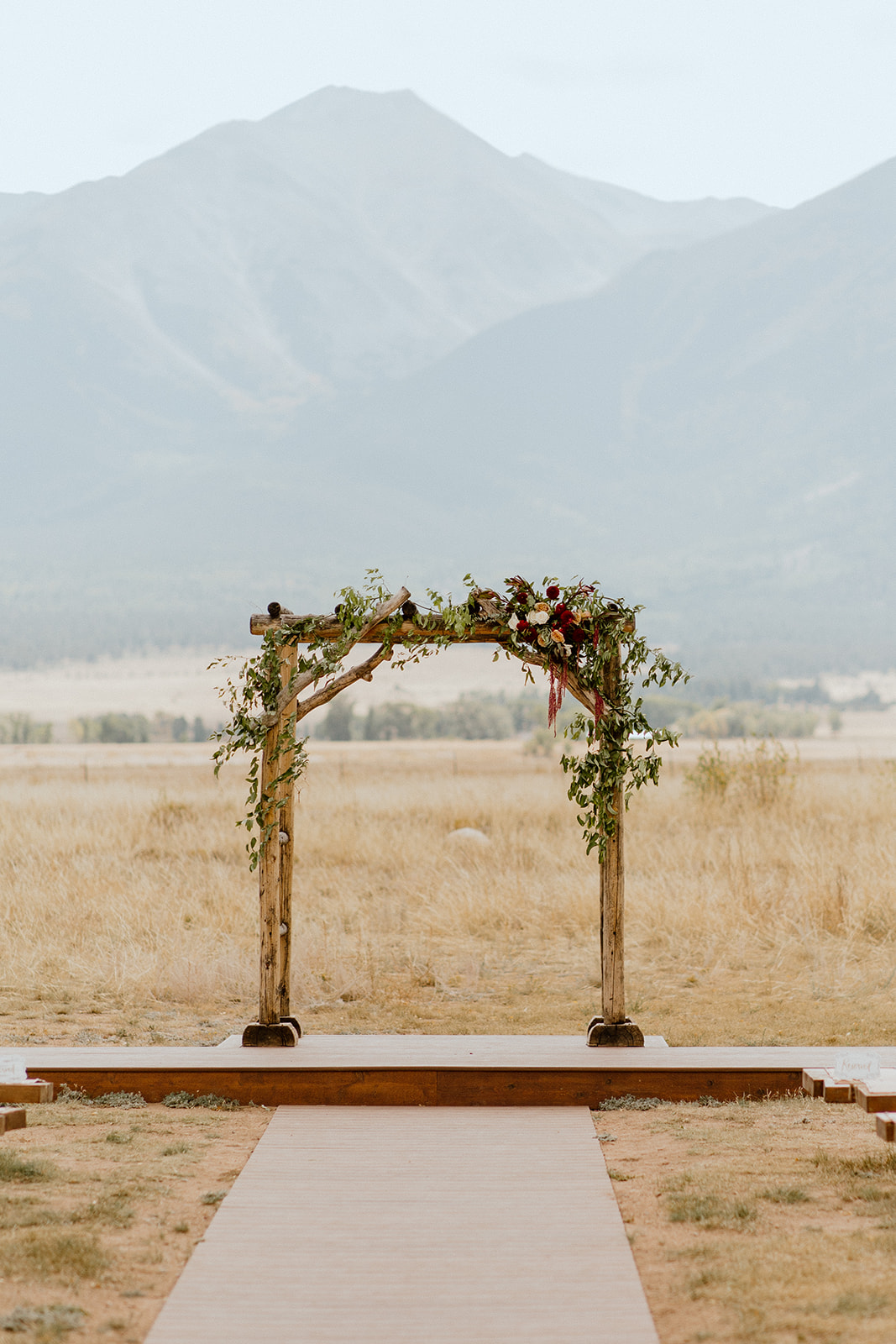 Wedding ceremony arch decorated with flowers with the Collegiate Peaks in the background. 