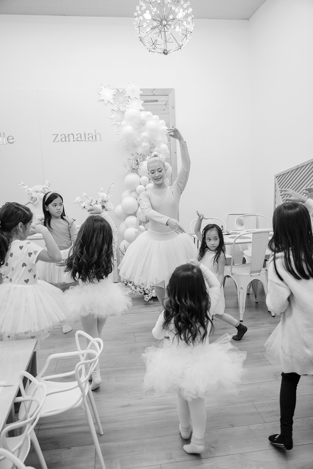 Ballet instructor teaching ballet to birthday girls and party guests.