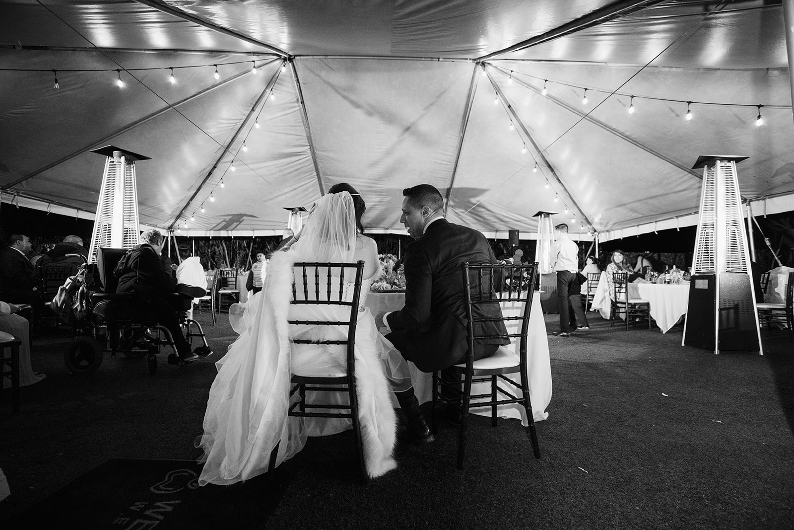 Black and white shot of the couple enjoying their tented wedding reception