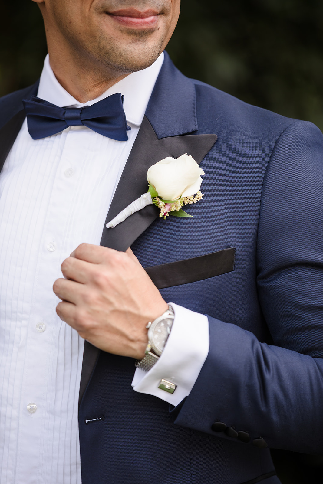 Closeup of groom's blue tux with black lapels and a white boutonniere