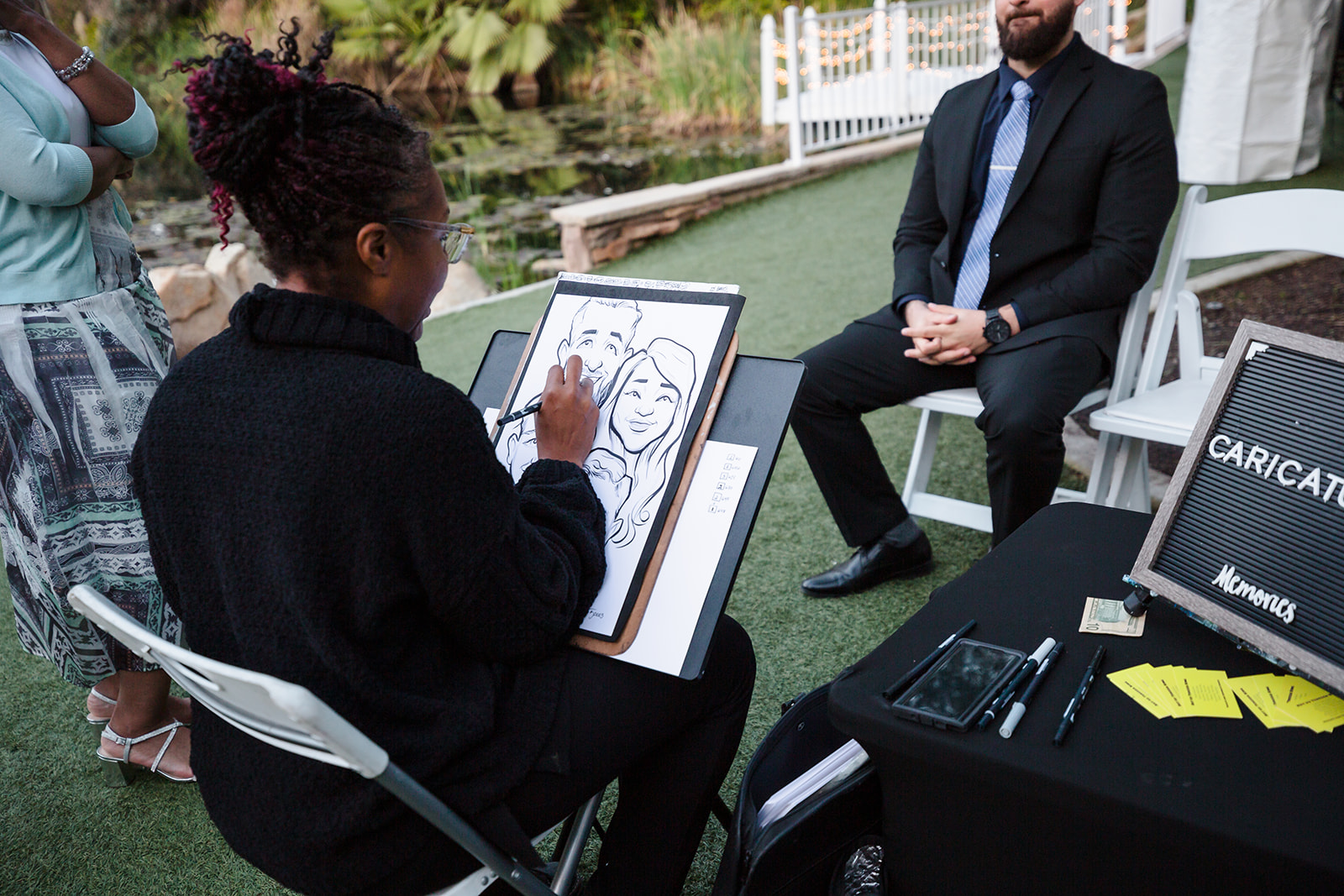 Caricature artist draws a wedding guest and their family during the reception