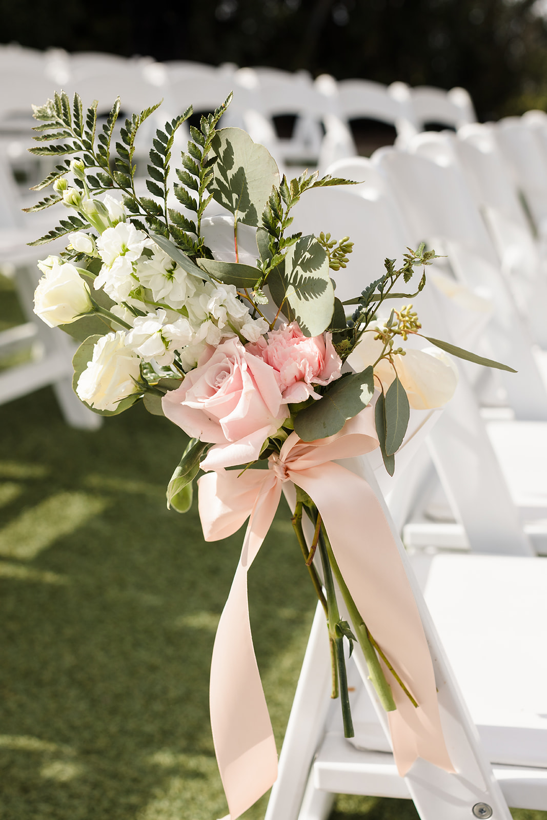 Pink and white flowers line the ceremony aisle at The Orchard.