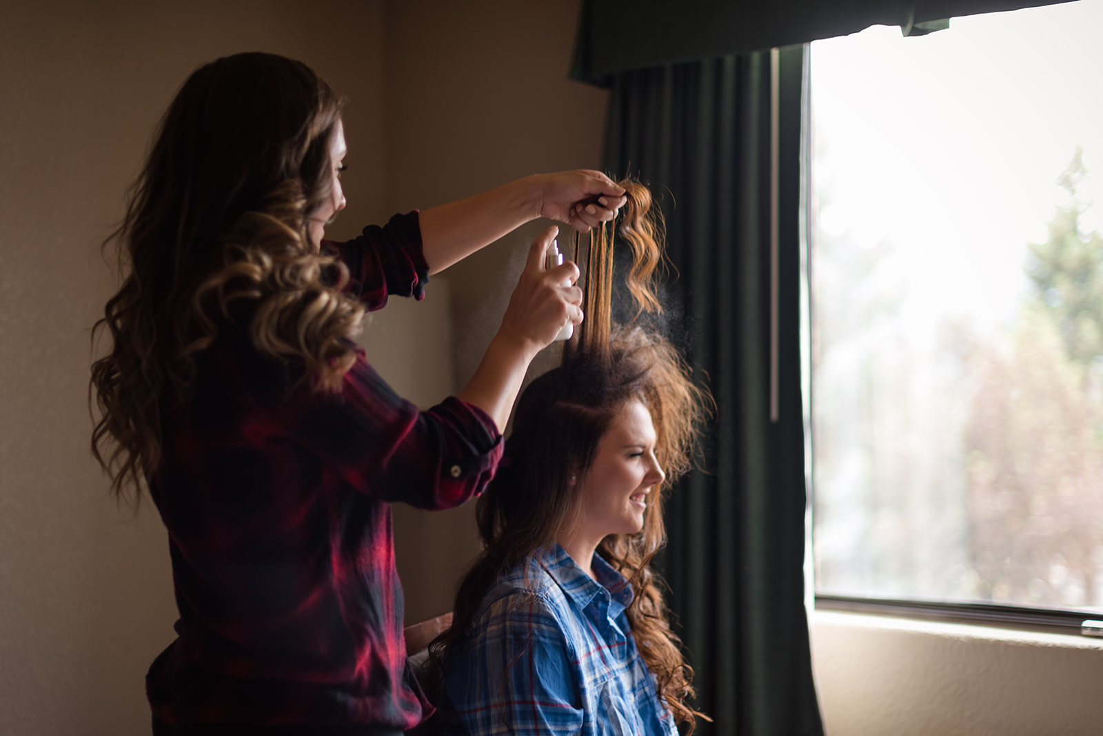 the bride has her hair done by one of her bridesmaids