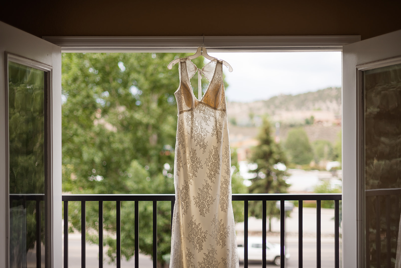 a wedding dress hangs in the doorway before the bride gets dressed for her backyard wedding in Colorado