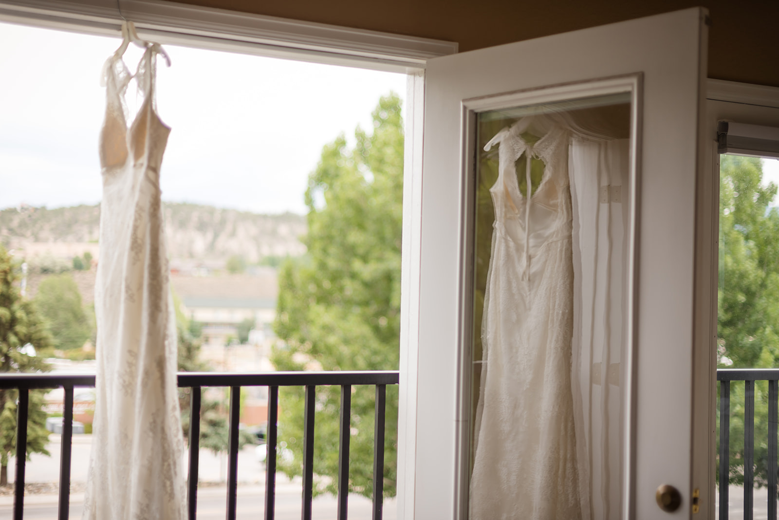 a wedding dress hangs in the doorway before the bride gets dressed for her backyard wedding in Colorado