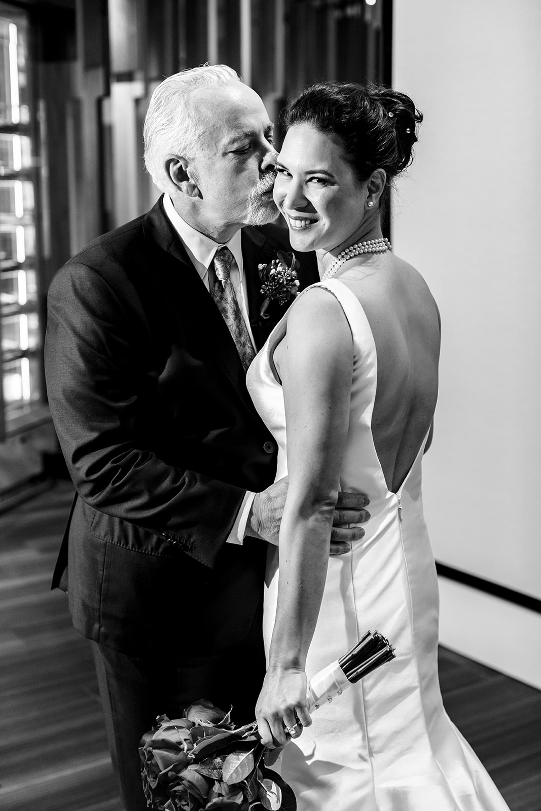 Groom kisses bride as she looks over her shoulder
