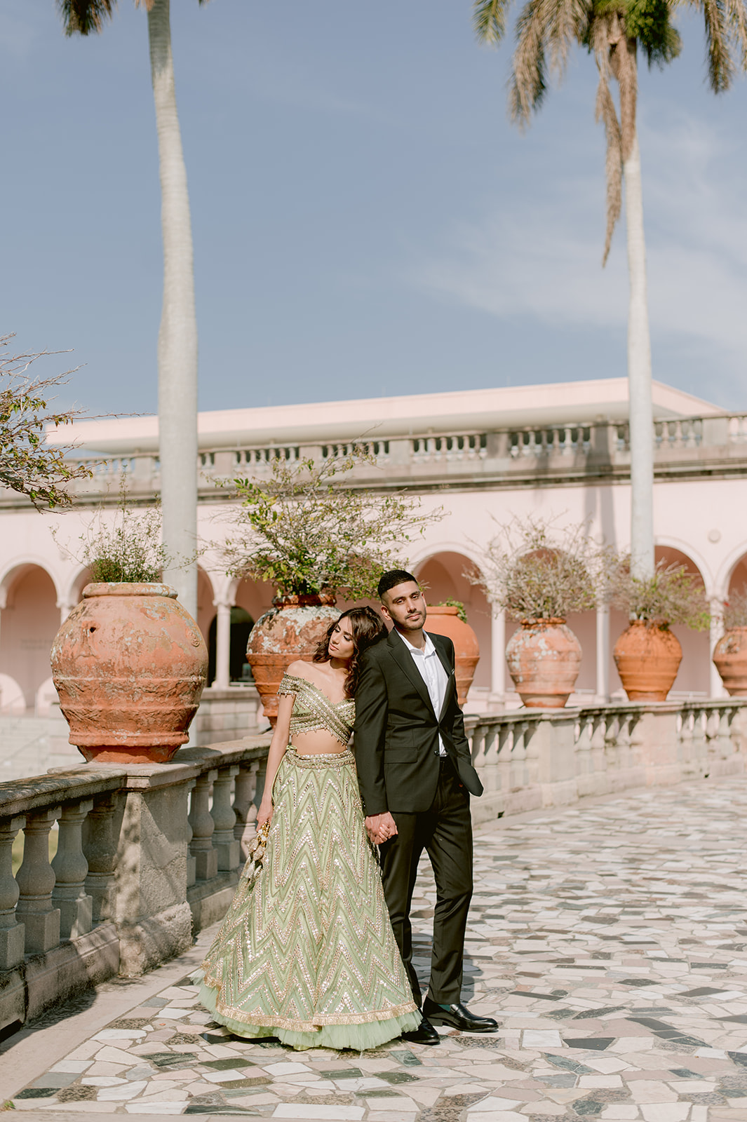 "Indian bride and groom in traditional attire embrace during their engagement session at the Ringling Museum"
