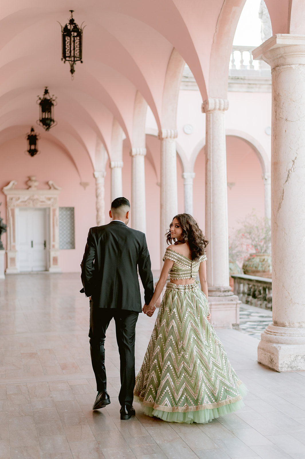 "Indian couple holding hands in front of Ca' d'Zan for their engagement shoot"
