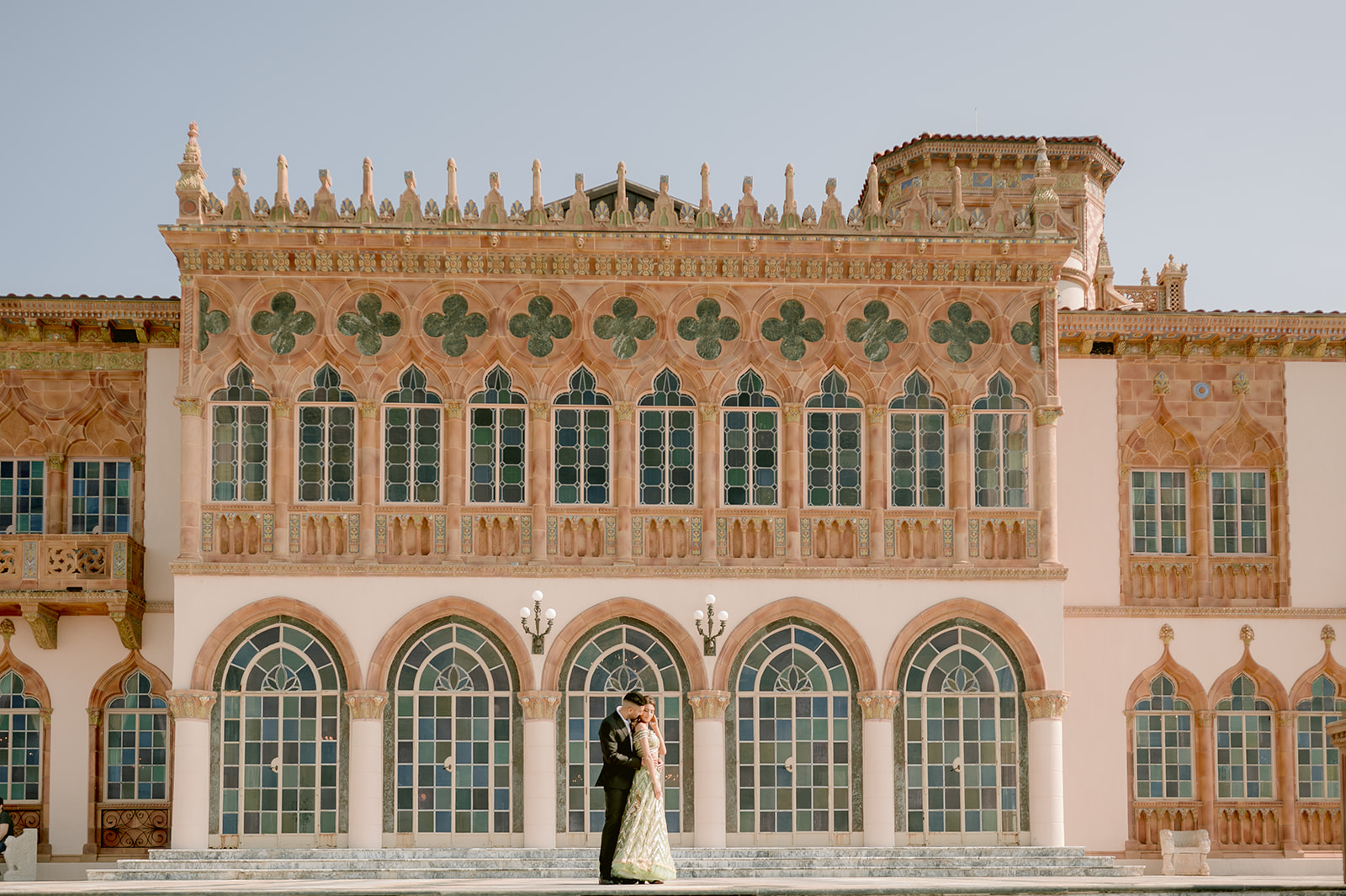 "Indian couple in traditional attire poses in front of the breathtaking scenery of the John and Mable Ringling Museum"
