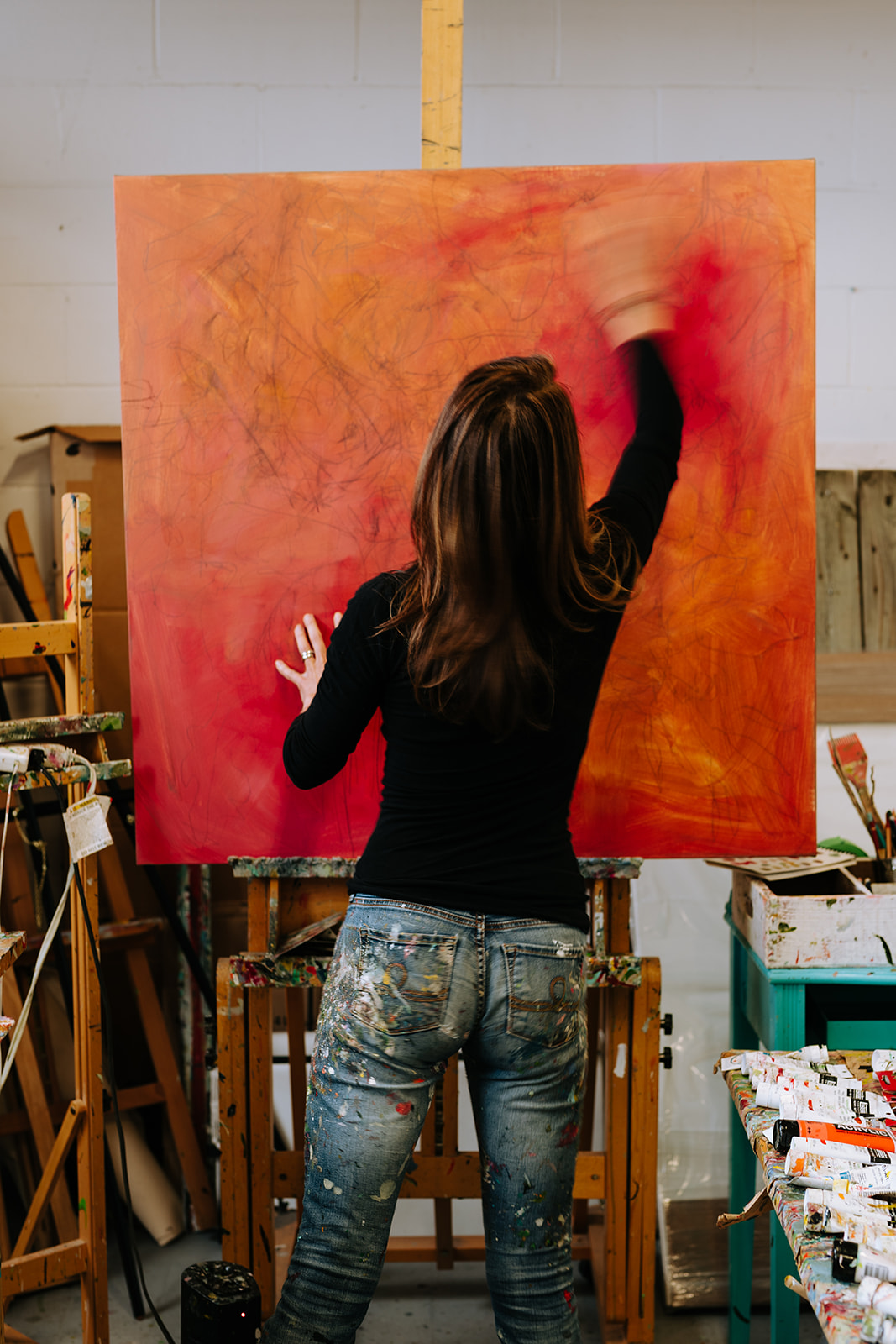 woman painting bright orange canvas