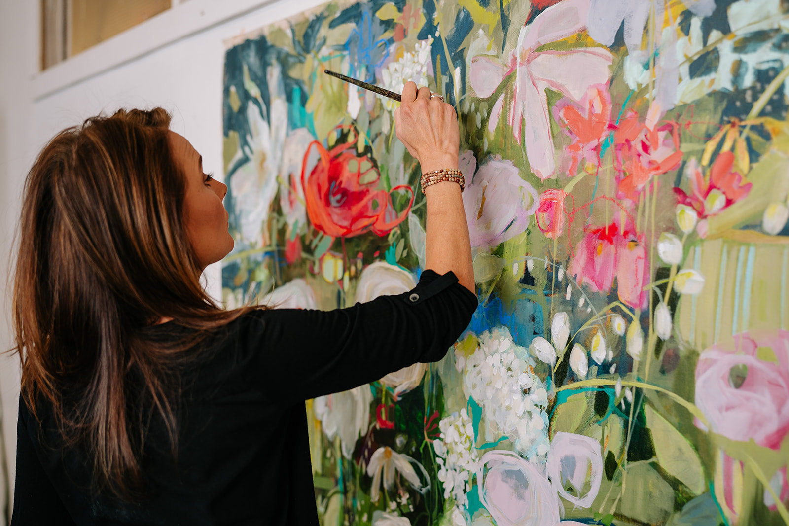 woman painting floral canvas