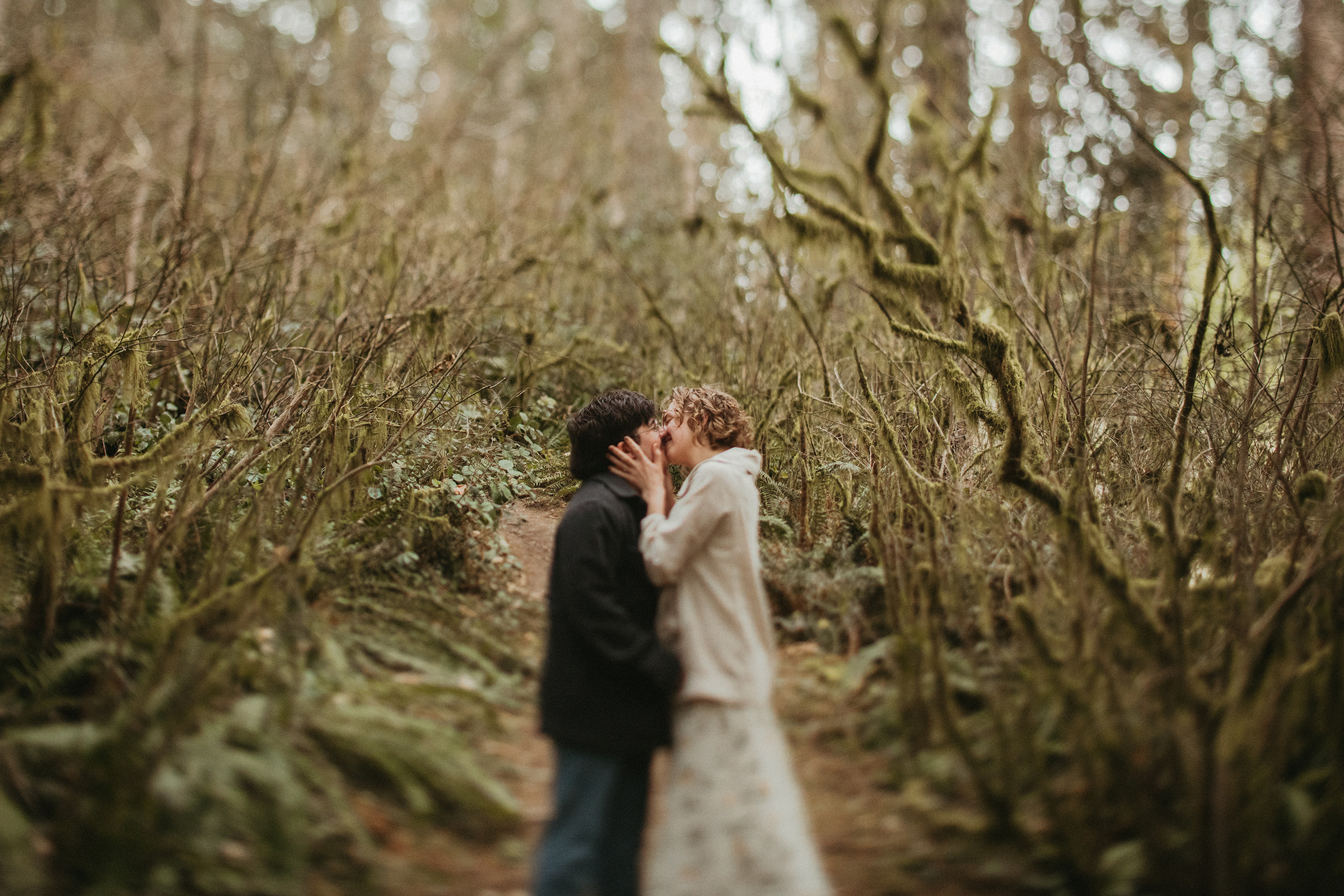Couple kissing inside mossy trees 