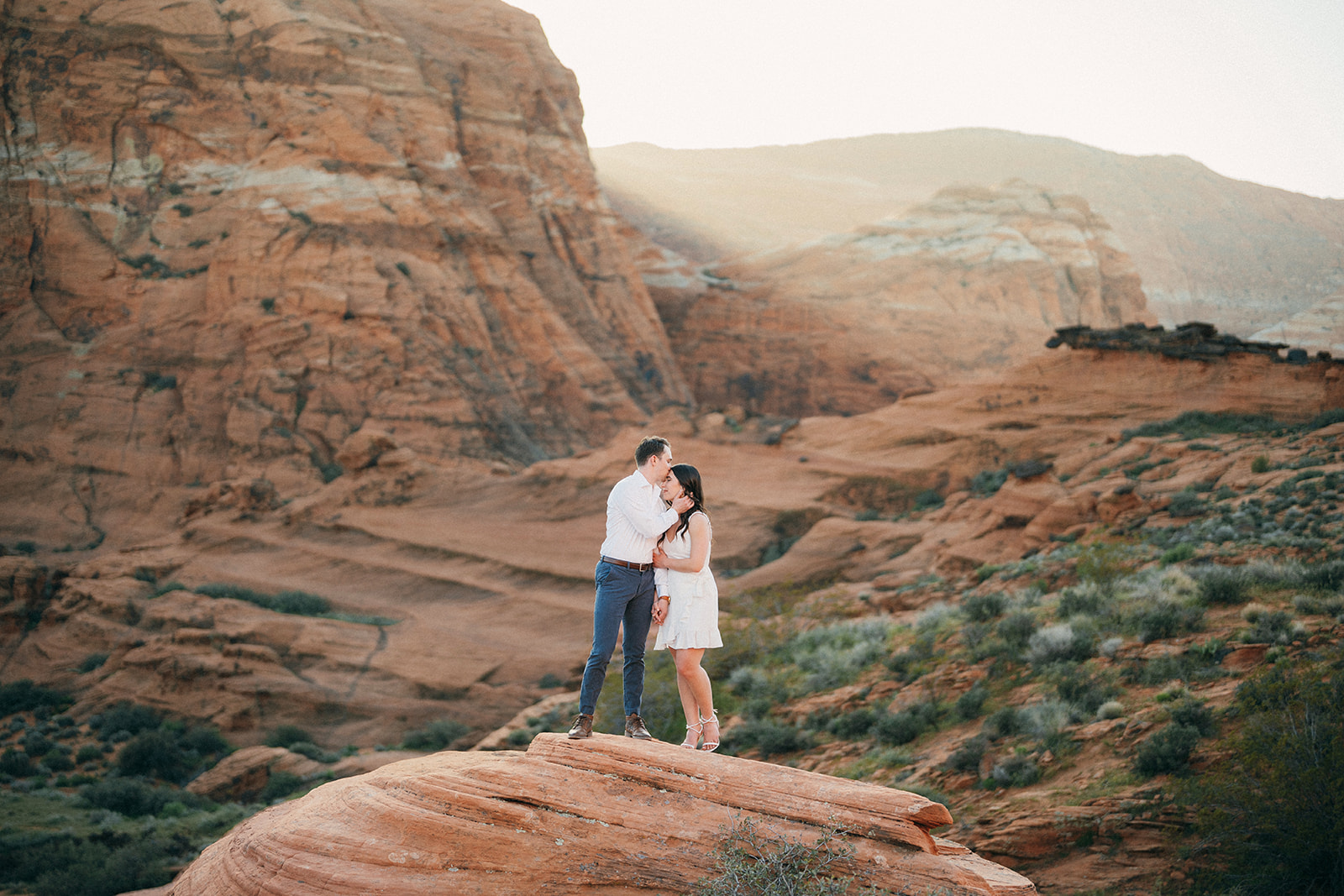 couple stands in front of red rock cliffs