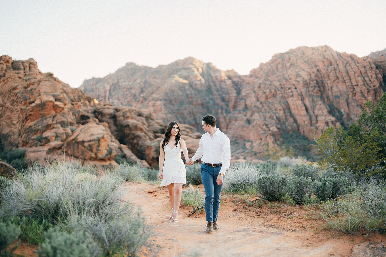 engaged couple walking in snow canyon