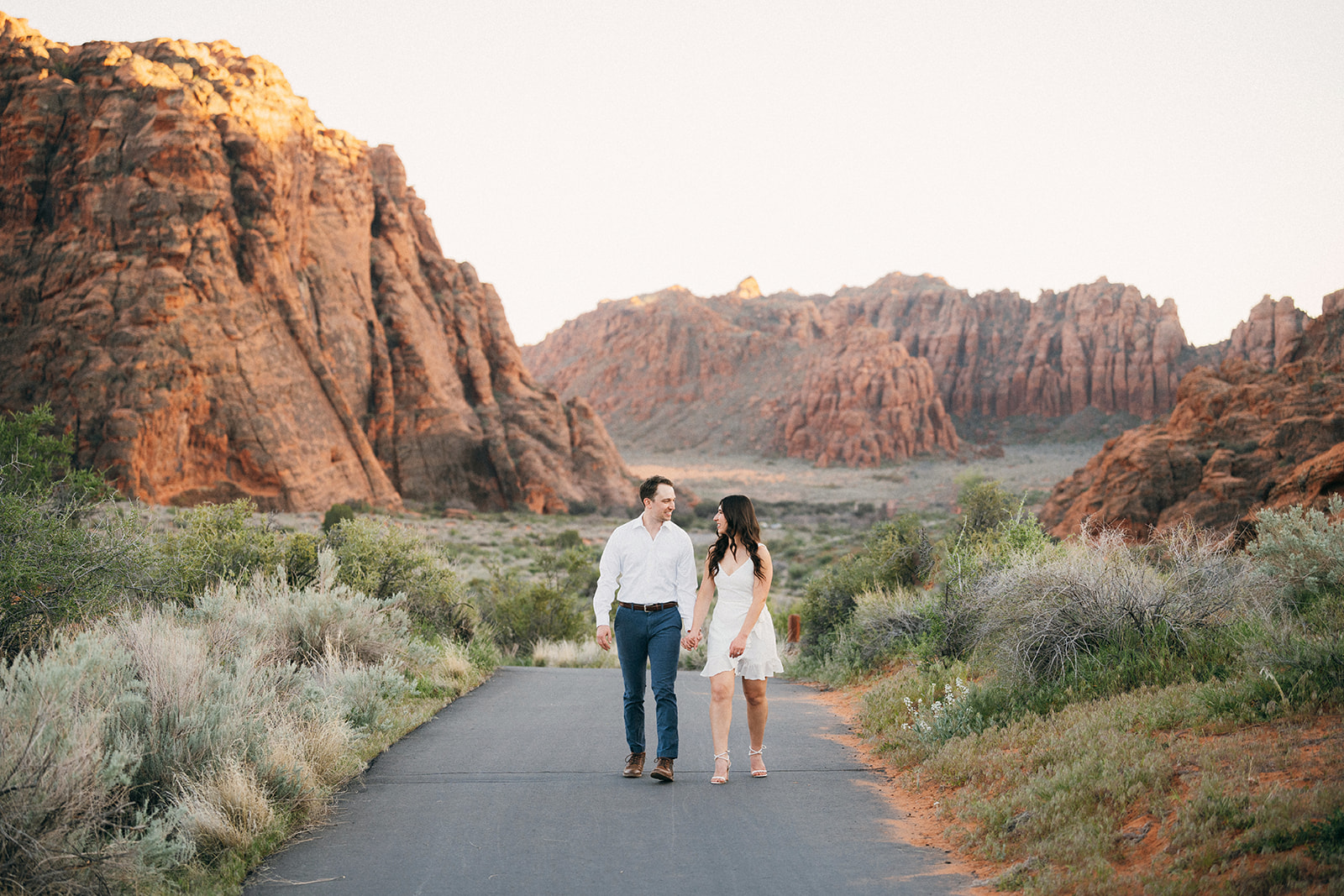 engaged couple walks down road in snow canyon