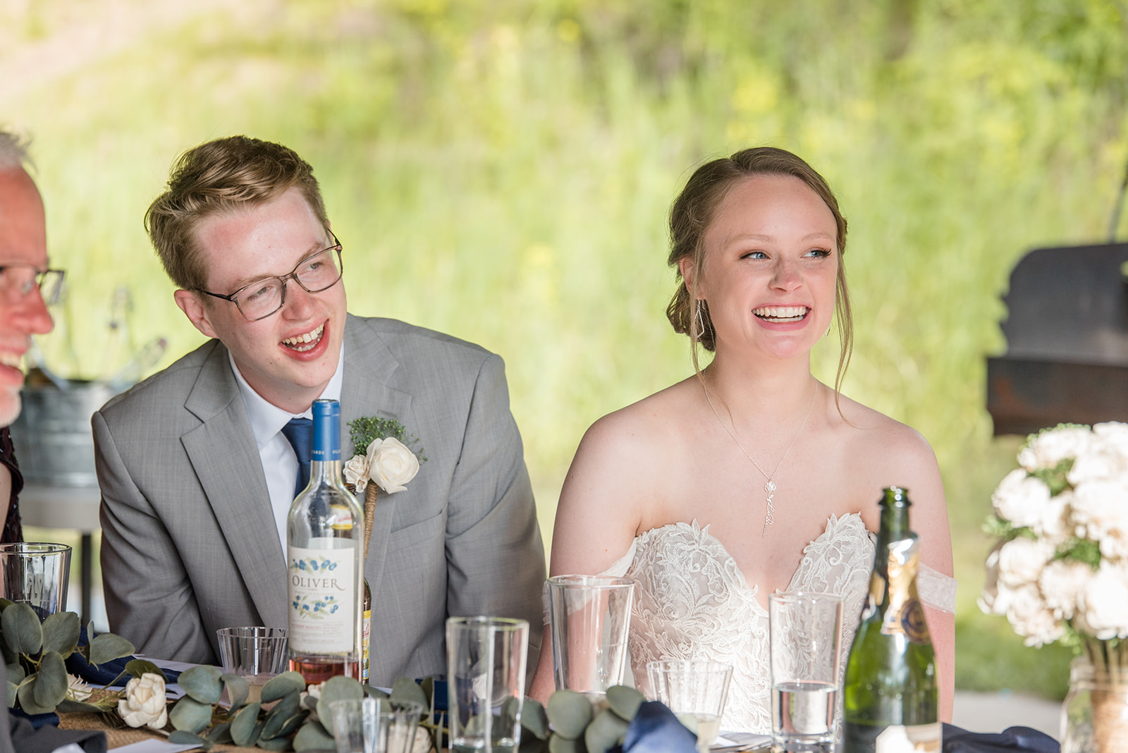 The bride and groom laugh during the toasts at their spring park wedding