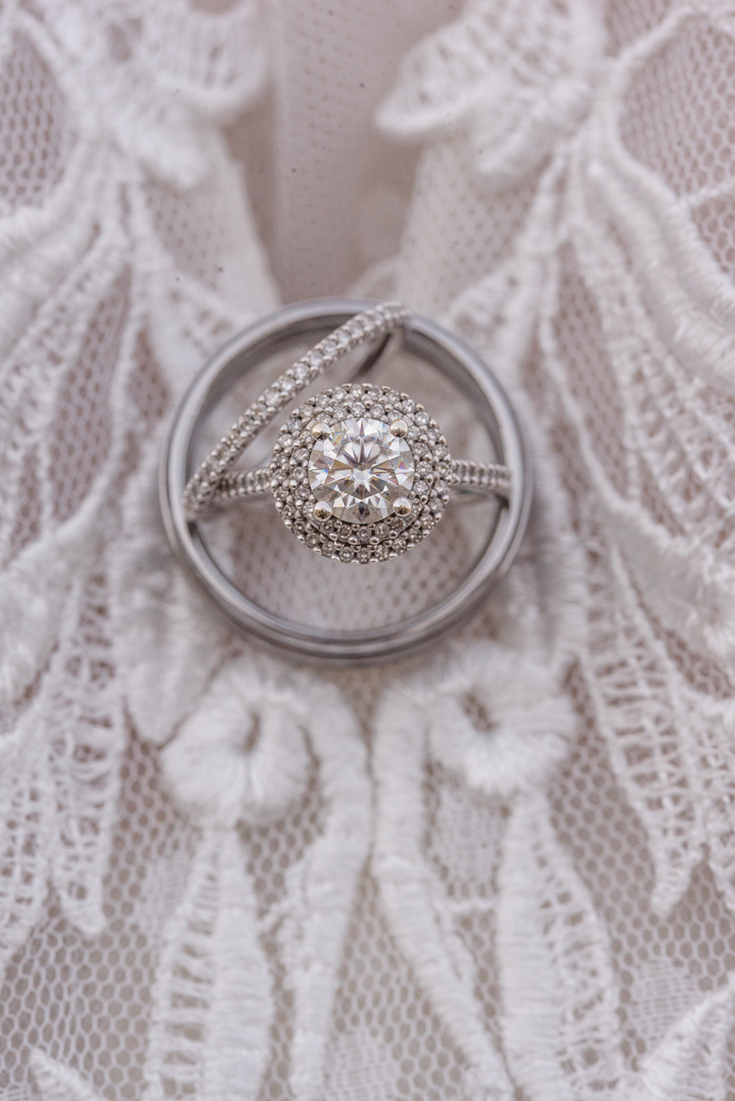 Wedding rings sit on top of wedding gown embroidery details